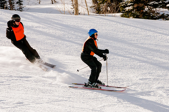Image of an 81 year old blind man skiing with his guide following.  Wasatch Adaptive Sports at Snowbird