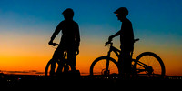 Mountain bikers overlook the city during sunset