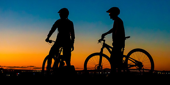 Mountain bikers overlook the city during sunset