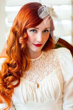 Vintage bride with beautiful red hair in front of back lit wooden blinds