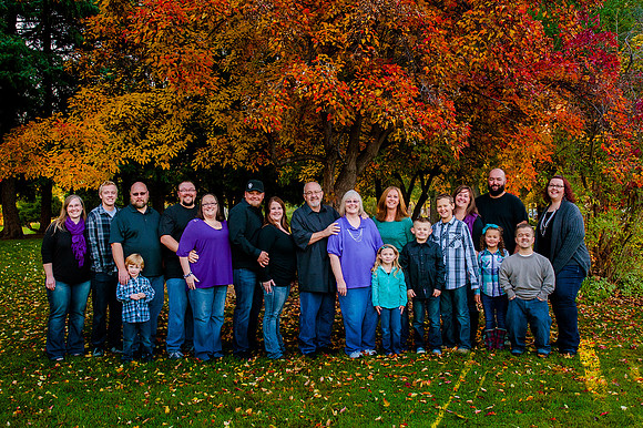 Large family portrait in front of colorful fall tree