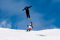 Groom jumping over his bride on skis