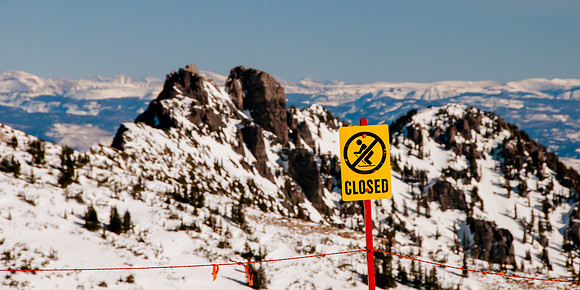 Closed marker with snow covered mountain background and blue sky at Snowbird