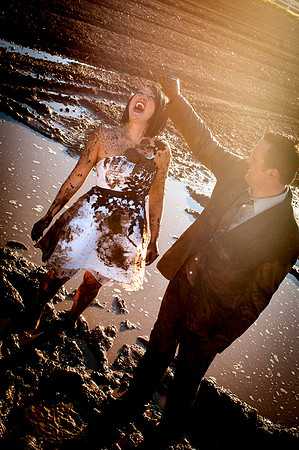 Groom squishes handful of mud on bride's head