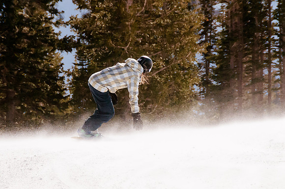 Veteran Snowboarder reaching down to get a piece of the wind blown powder at Snowbird.