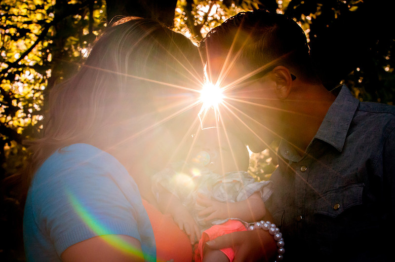 New family of 3 embracing in a sunburst