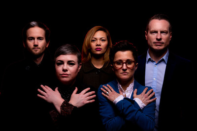 Five individuals standing in a row, with dramatic lighting from above creating shadows under their eyes and mouths. They are backlit with a red rim light against a black background.