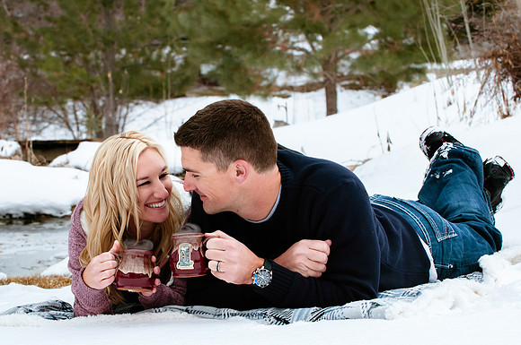 Couple enjoying hot cup of coffee while picnicing in a winter wonderland
