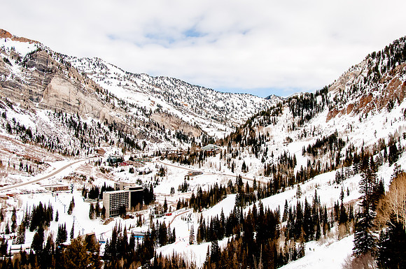 The Cliff Lodge at Snowbird with mountain background and blue, cloudy sky.