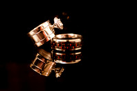 Detail shot of bride and groom's rings on a black piano with reflection