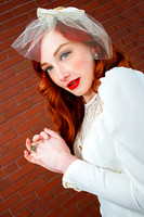 Vintage bride with red hair in front of a red brick wall