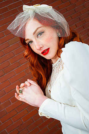 Vintage bride with red hair in front of a red brick wall