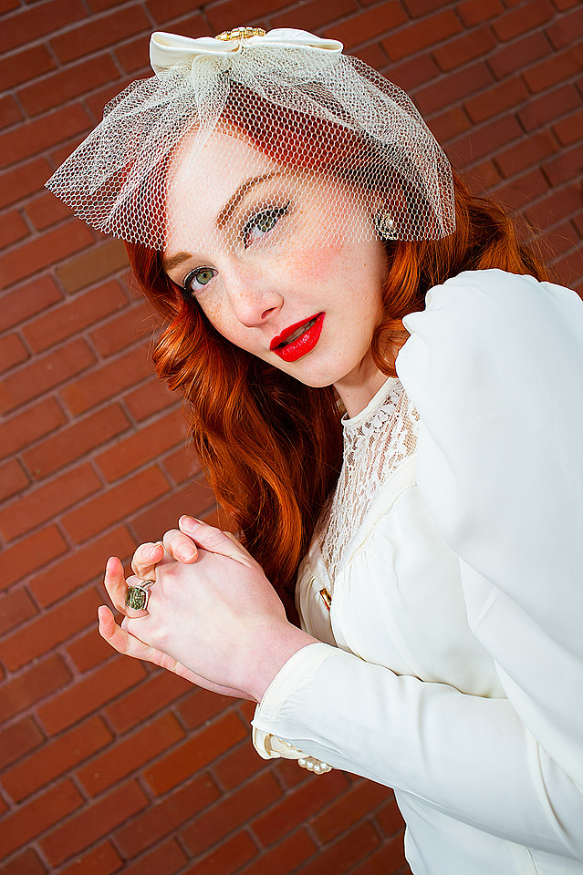 Vintage bride with red hair in front of a red brick wall
