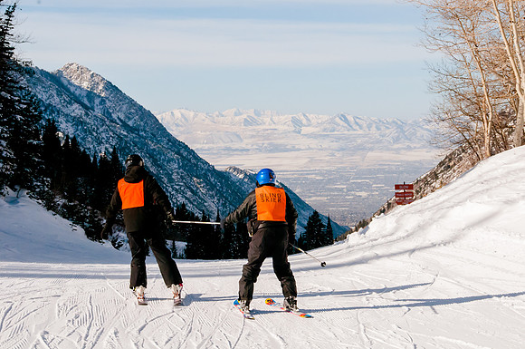 Image of an 81 year old blind man skiing with his guide. Wasatch Adaptive Sports at Snowbird.  View of Salt Lake City, Utah