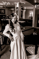Black and white 40's vintage bride leaning against piano with wedding dress wrapped around piano leg