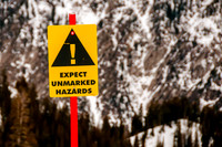 Warning Sign Expect Unmarked Hazards with blury mountain background.