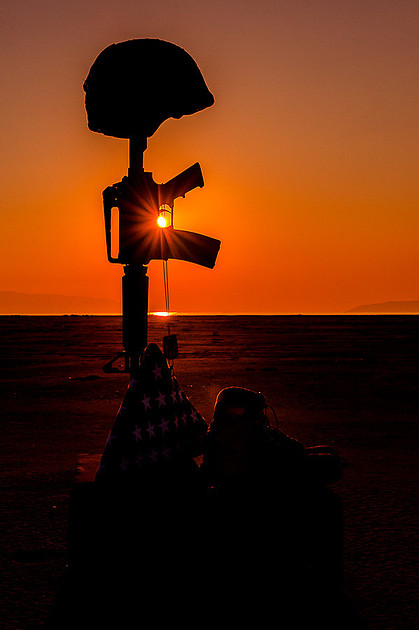 Field cross with setting sun flaring through trigger guard