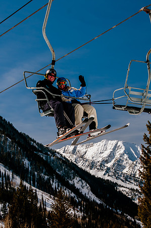 Portrait of skiers on lift with snow covered mountain background.