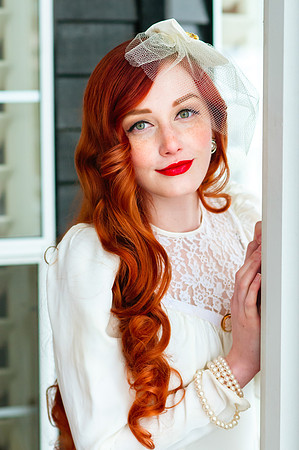 Bride with red hair poses in front of a cool colored background